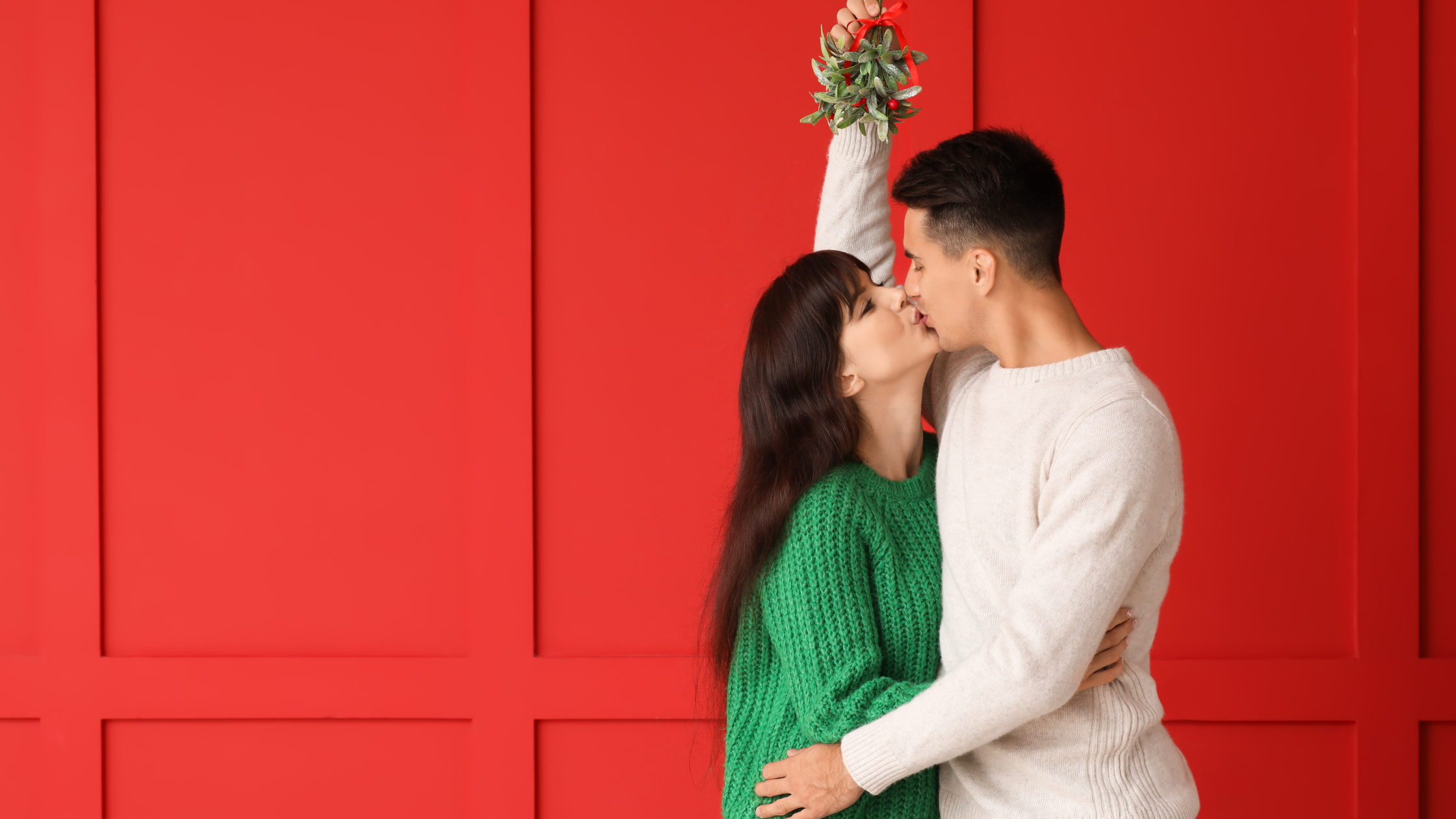 Una pareja se besan bajo el muérdago, una tradición navideña 