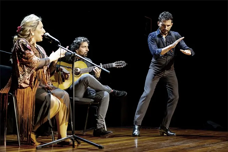 Un bailaor flamenco taconea al ritmo de un grupo de flamenco
